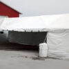 20' x 50' Frame tent with partial side walls and water barrels used for ballast/tent anchoring.