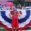 Young child holding a flag of the United States of America with one of our Bunting flags in the background.