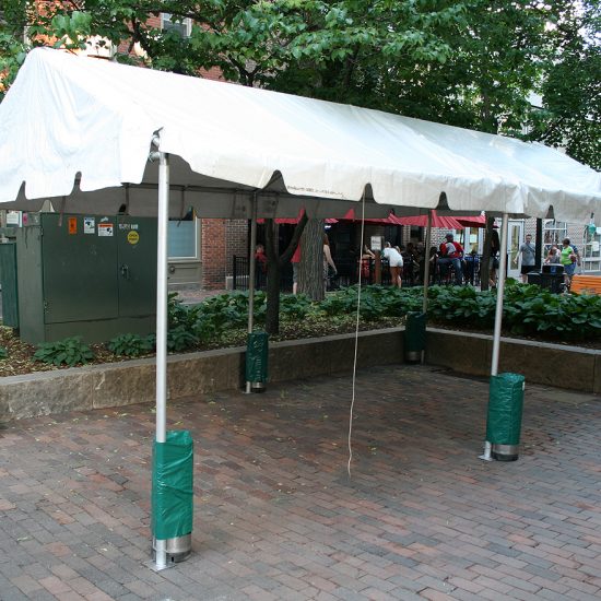 Frame tent with covered, 73 lb. canister weights used as tent ballast.