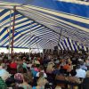 View from inside the 60' x 150' Gala Rope and Pole tent with a large crowd of people.