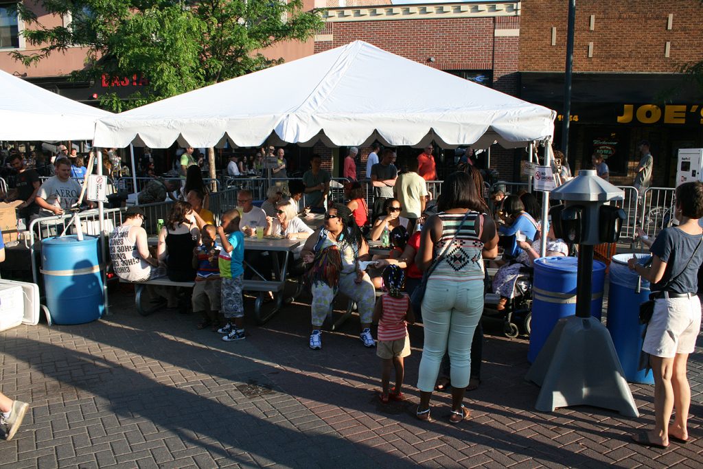 Picnic tables under a frame tent at the 2014 Iowa Arts Festival.