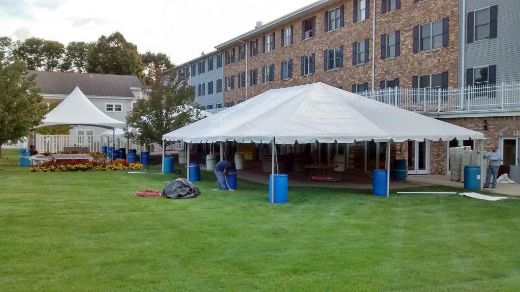 Multiple frame tents set up for event with water barrels