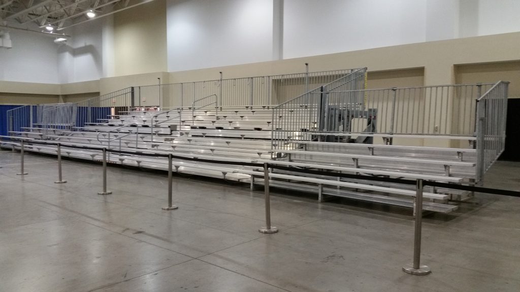 45' towable hydraulic bleacher flanked by two 5-row bleachers, stanchions, plus pipe and drape.