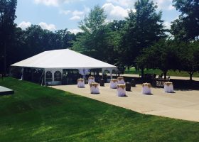 Outside of wedding tent with tables wine barrels and bar