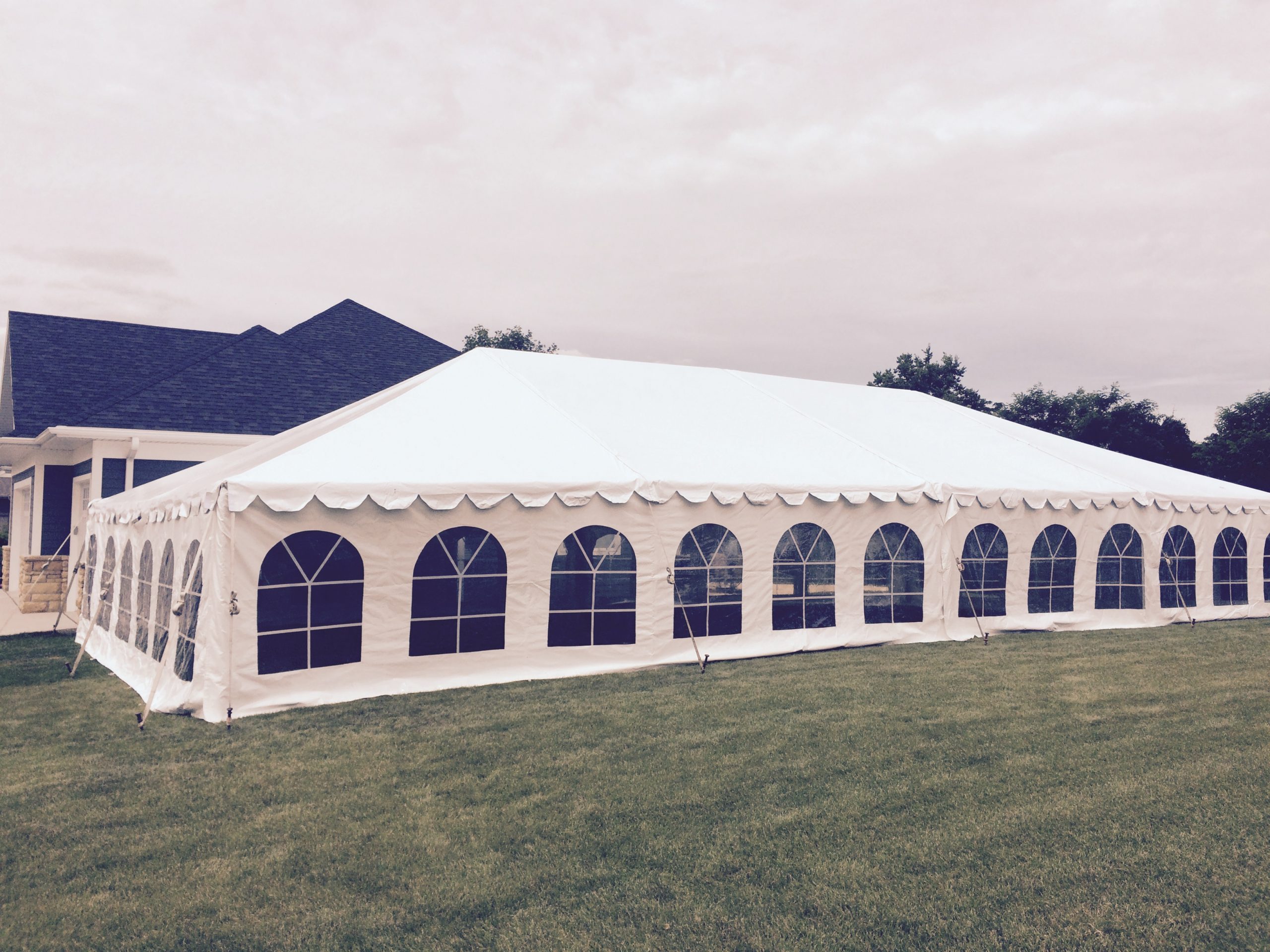 Side of 30' x 60' frame tent in side yard for wedding reception next to a home
