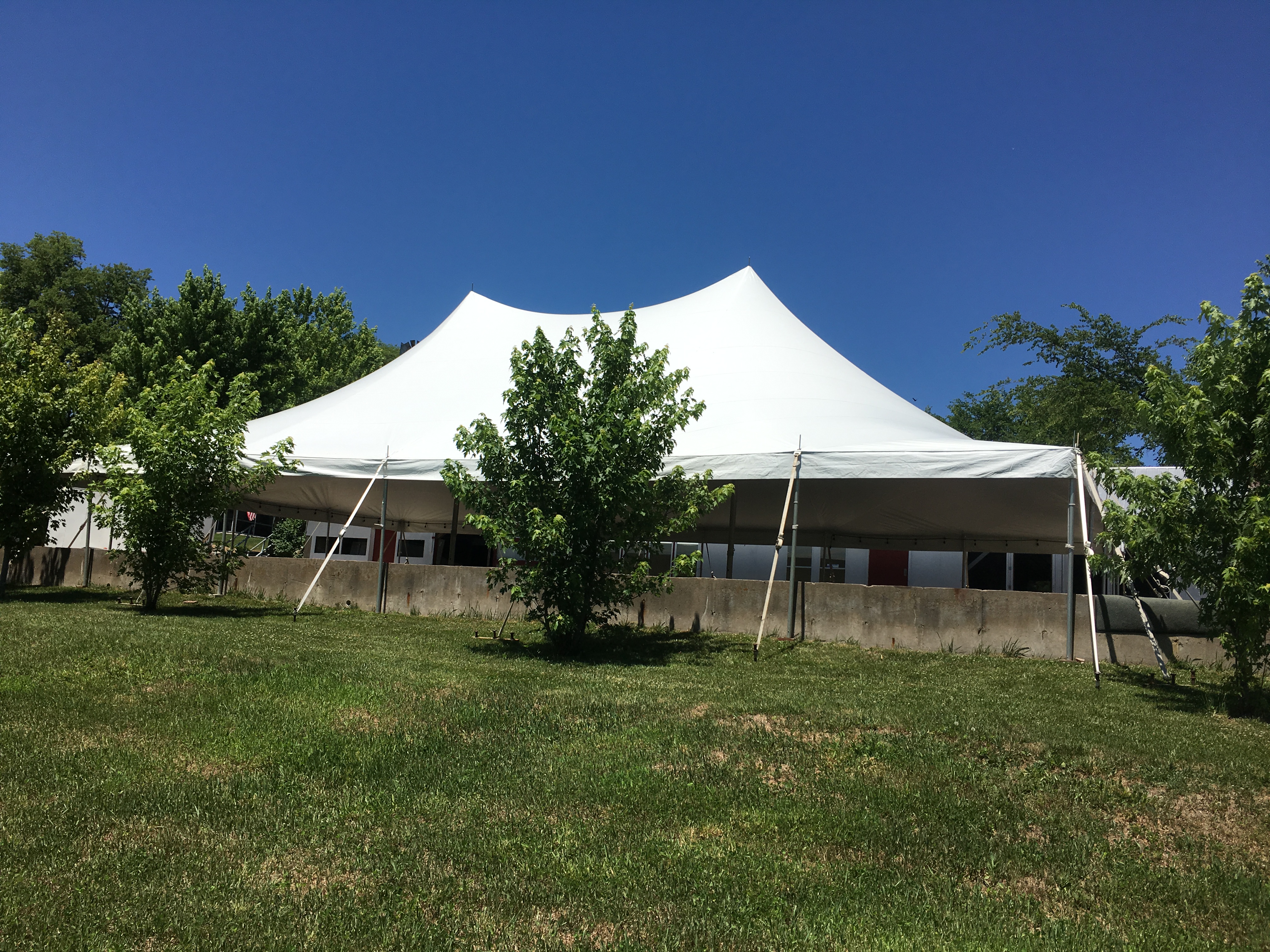 40'x60' Rope and Pole Tent with concrete wall obstruction at an outdoor wedding reception in Columbus Junction, IA