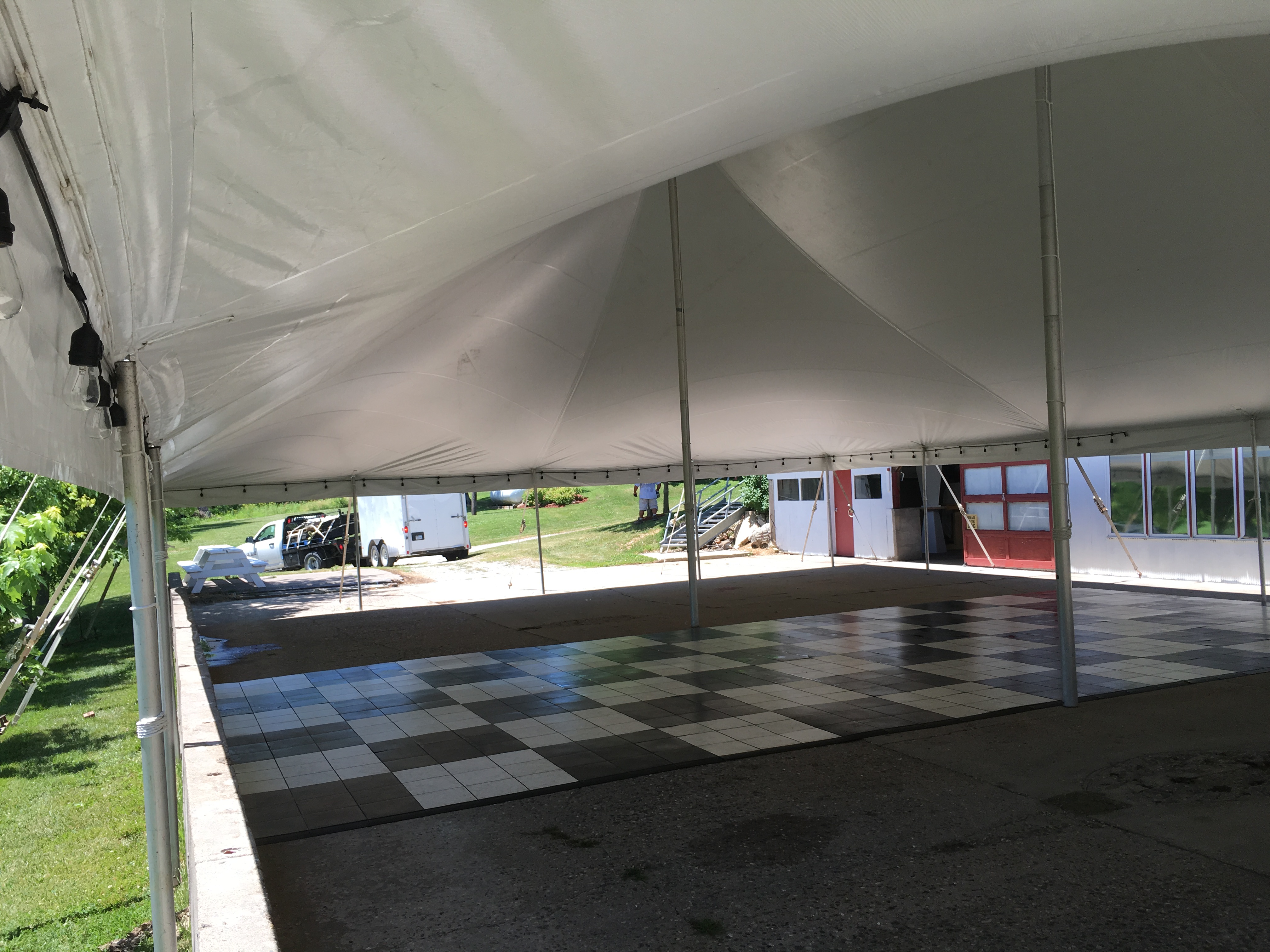 Under 40'x60' Rope and Pole Tent with concrete wall obstruction at an outdoor wedding reception in Columbus Junction, IA