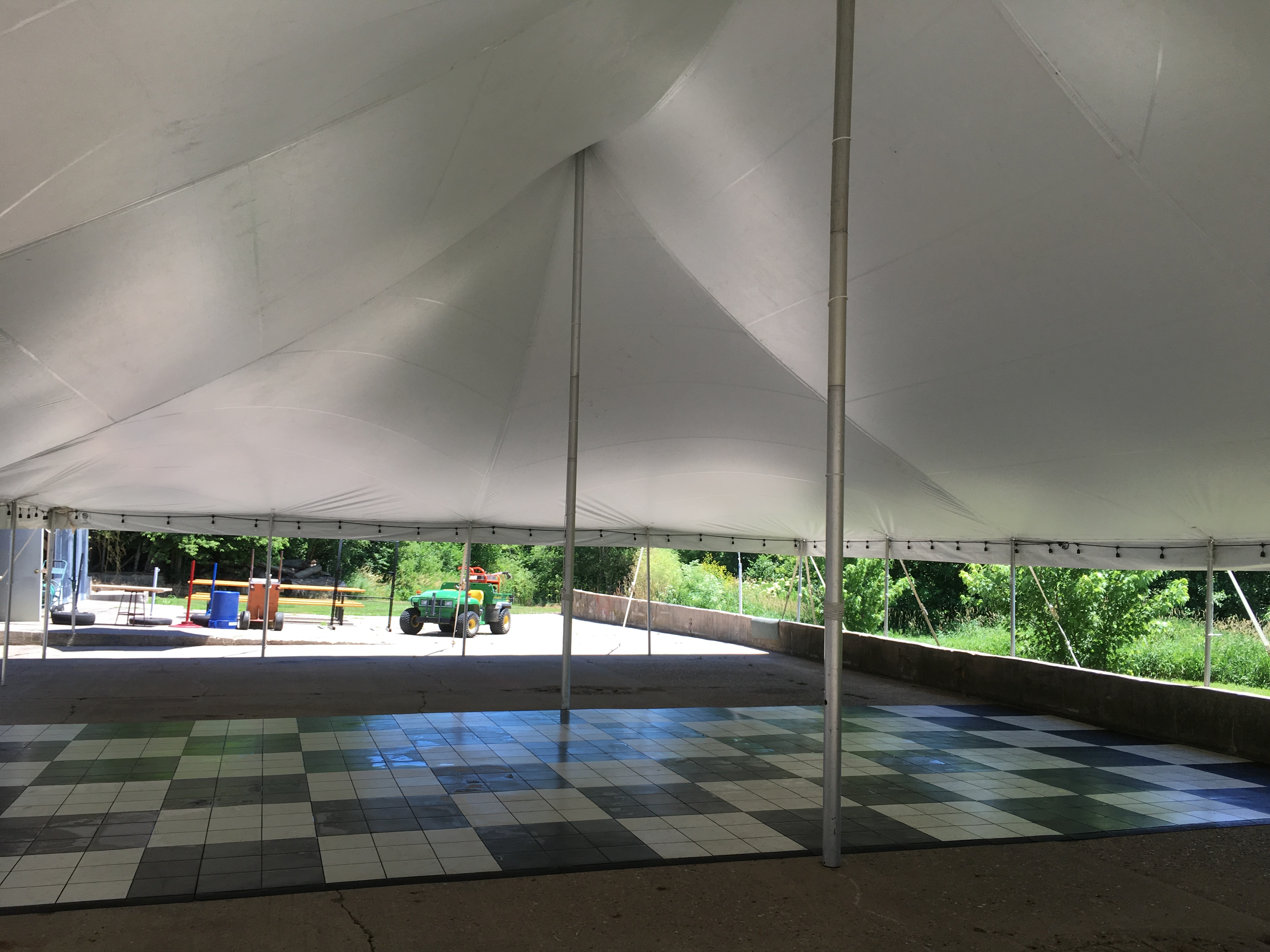 Under the 40'x60' Rope and Pole Tent with dance floor at an outdoor wedding reception in Columbus Junction, IA