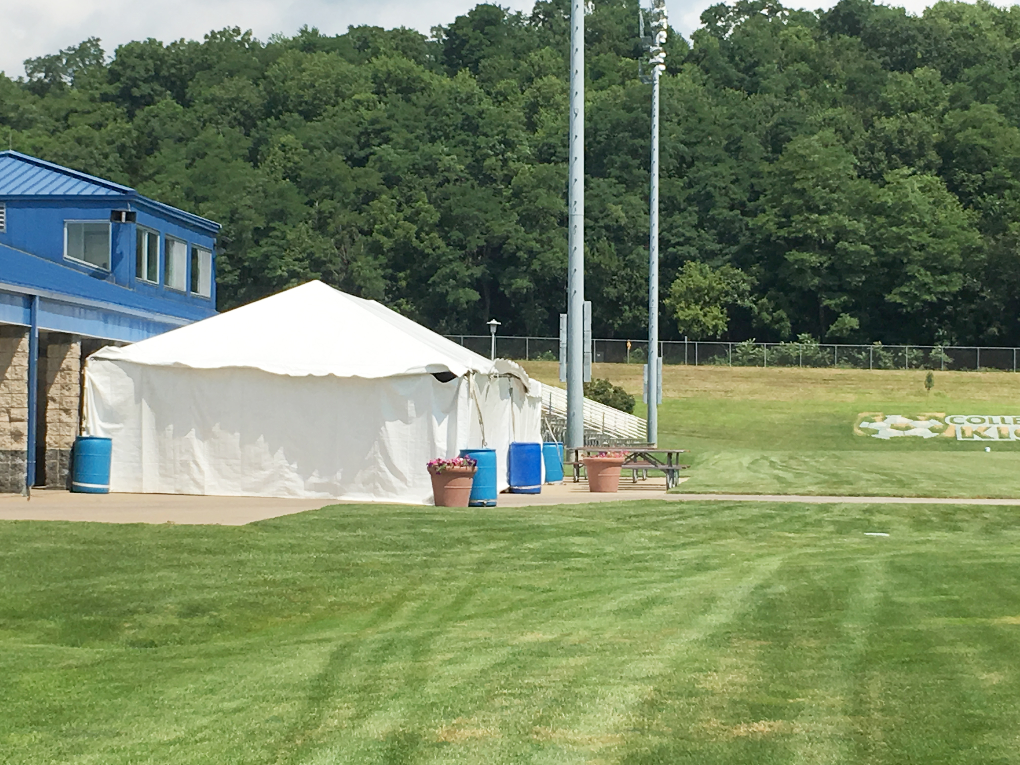 Frame tent with side walls with ballast of water barrels at the Muscatine Soccer Complex