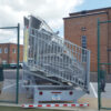 Towable bleachers being delivered though a small gate with spotters