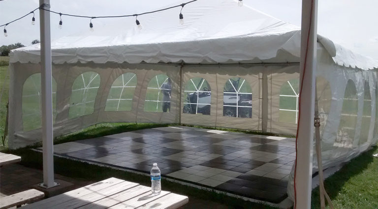 50s style anniversary party with black and white checked dance flooring under a tent