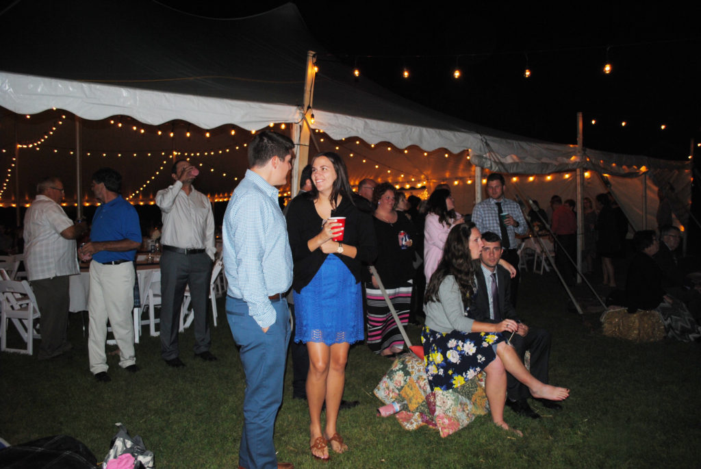 People outside 60' x 90' rope and pole wedding tent at night