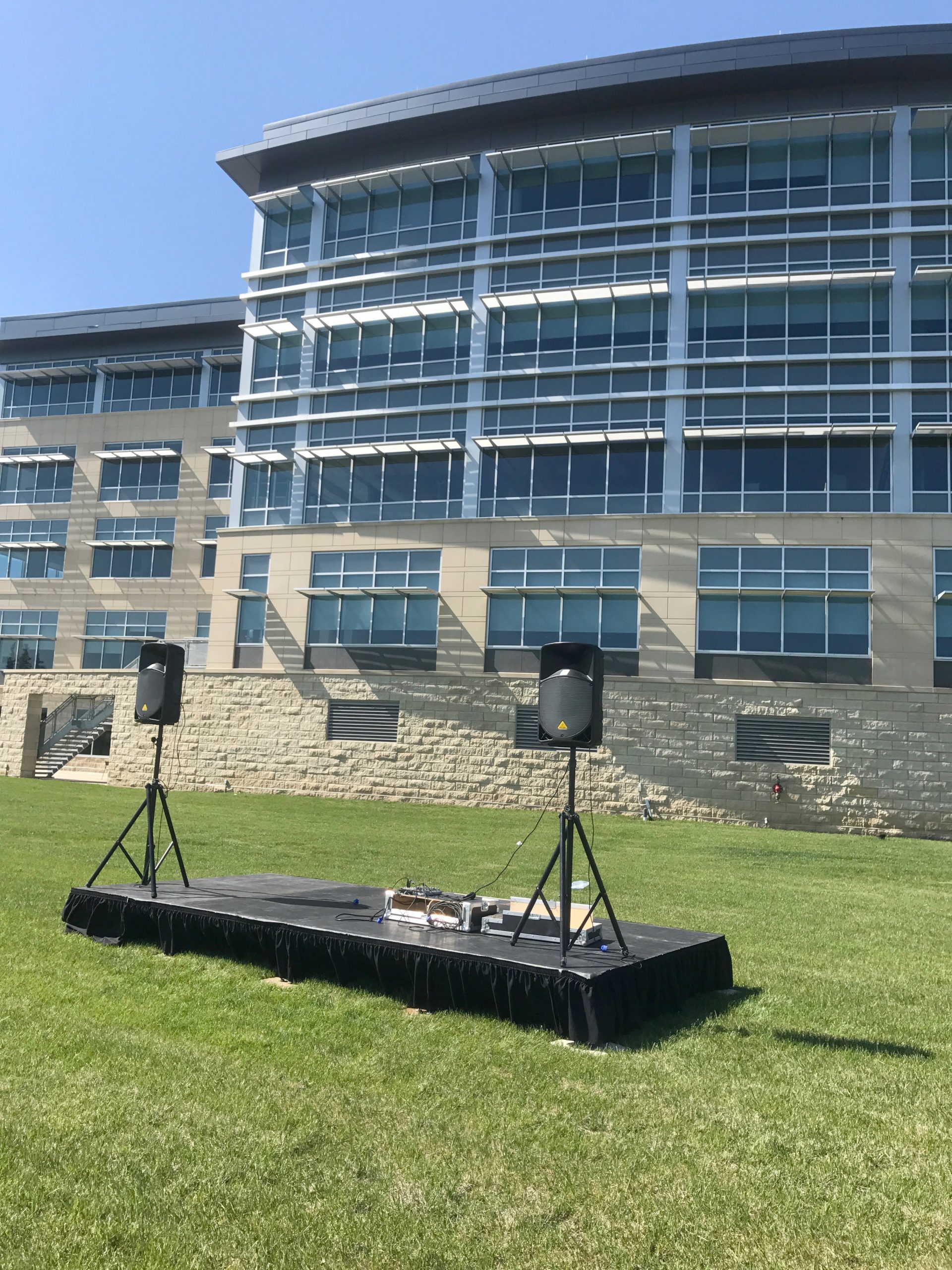 8' x 16' stage with PA Pro Package and tripod stands behind UICCU Financial Center Building in North Liberty, Iowa