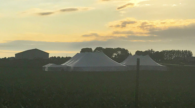 Event with 20' x 60' frame tent with a glass door on the left with 80' x 150' rope and pole and 60' x 90' rope and pole tent on the right with two 10' x 10' frame tents connecting them all together