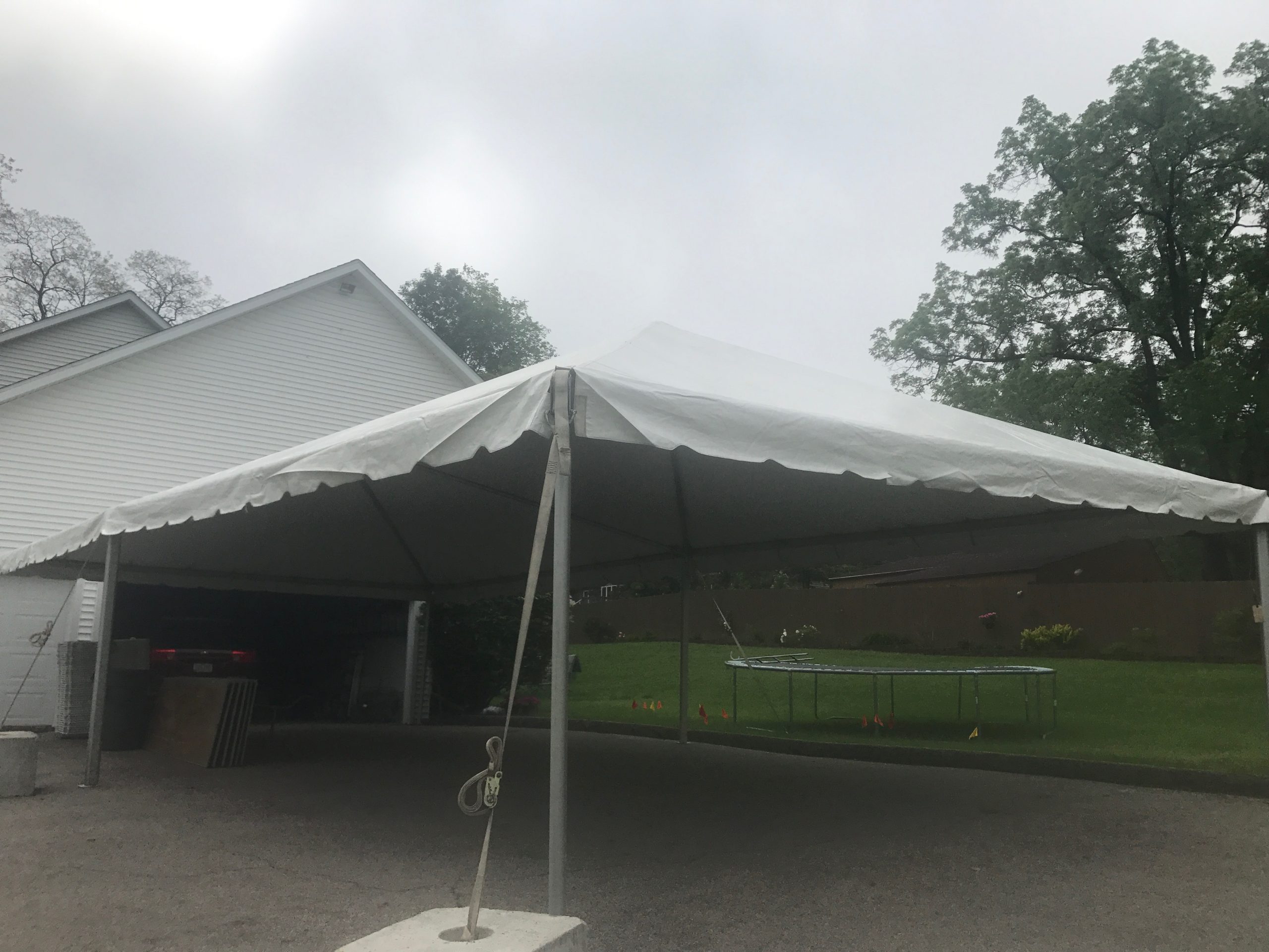 Looking under 20' x 40' frame tent next to a home for Graduation Party