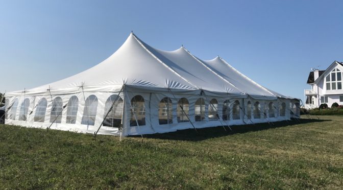 Side of 40' x 80' rope and pole wedding tent setup in Fairfield, Iowa with building in the background
