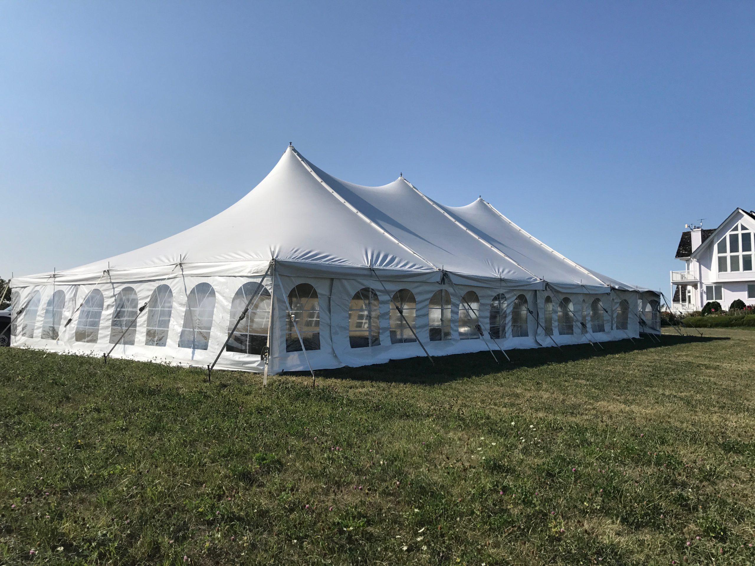 Side of 40' x 80' rope and pole wedding tent setup in Fairfield, Iowa with building in the background
