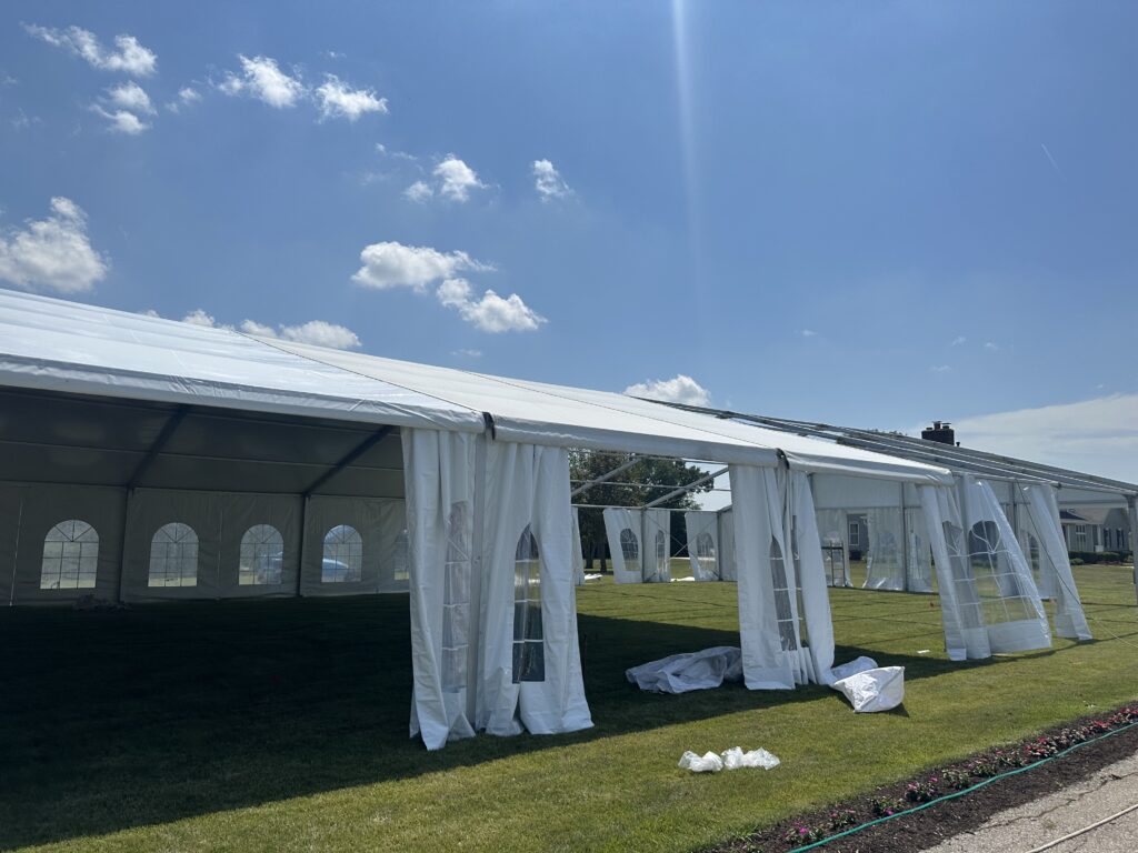 Adding the top to a 18m x 35m (60′ x 114′) Losberger clearspan temporary event tent structure for a wedding reception in Iowa City near Solon, IA