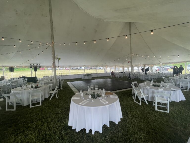 Head table, tables, chairs, and lights under a 60' x 90' legend twin-pole rope and pole tent.
