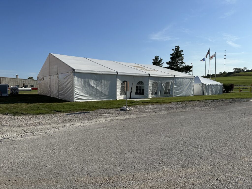 Outside of the 60′ x 66′ (18m x 20m) Losberger Clearspan Structure Temporary Tent on the left and 20' x 20' frame tent on the right