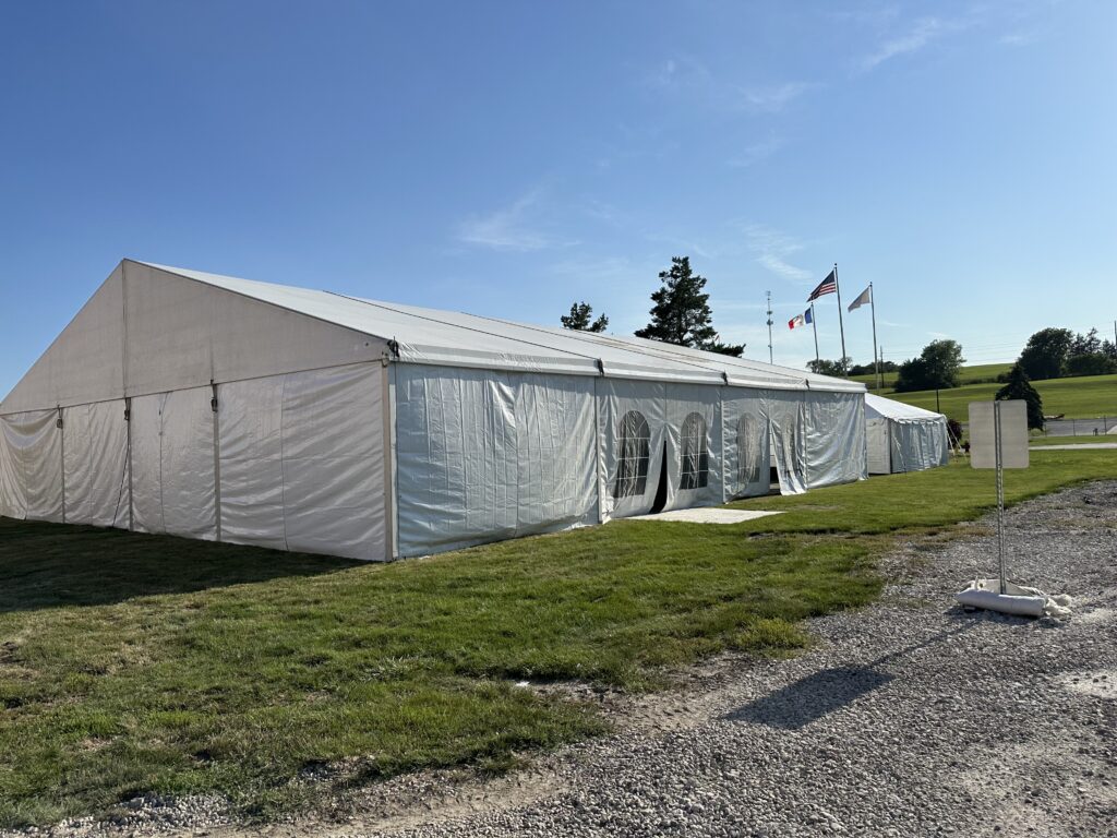Outside of the 60′ x 66′ (18m x 20m) Losberger Clearspan Structure Temporary Tent on the left and 20' x 20' frame tent on the right (closer)