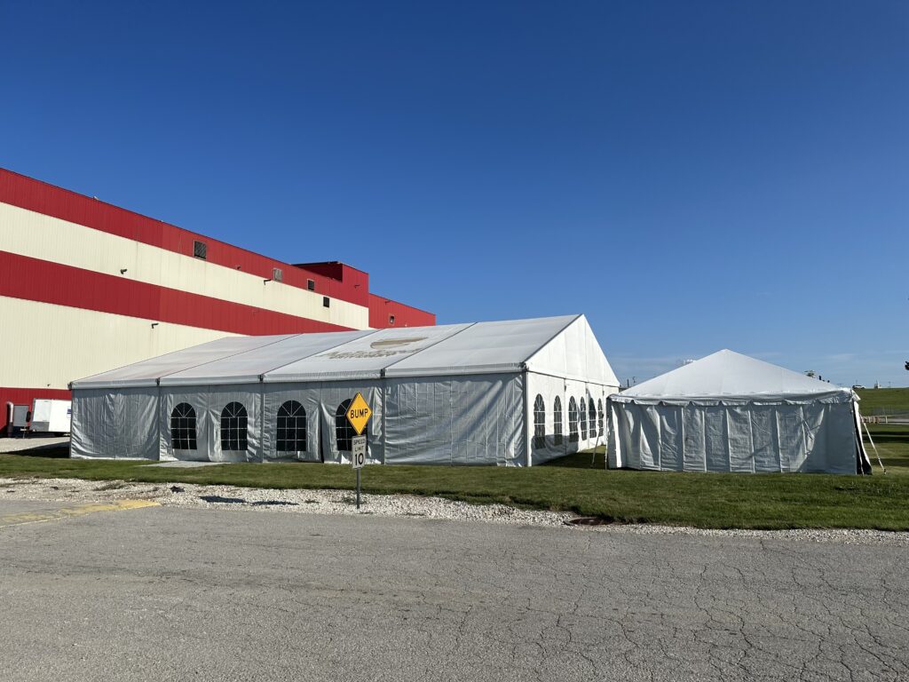 Outside of the 60′ x 66′ (18m x 20m) Losberger Clearspan Structure Temporary Tent on the left and 20' x 20' frame tent on the right (full)