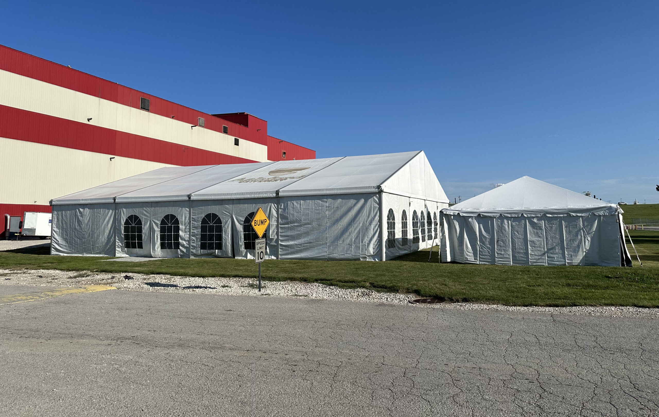 Outside of the 60′ x 66′ (18m x 20m) Losberger Clearspan Structure Temporary Tent on the left and 20' x 20' frame tent on the right (full)