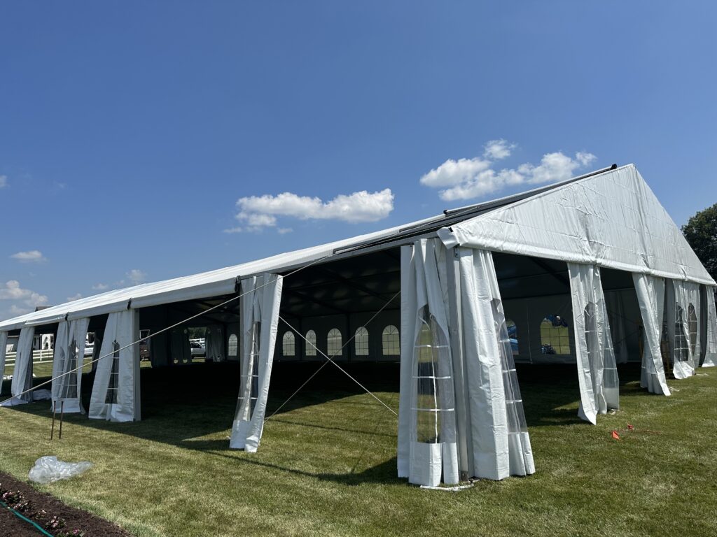 Pulling the last top on a 18m x 35m (60′ x 114′) Losberger clearspan temporary event tent structure for a wedding reception in Iowa City near Solon, IA