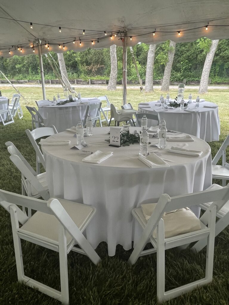 Round tables and chairs under a 60' x 90' legend twin-pole rope and pole tent.