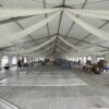 Under the 18m x 35m (60′ x 114′) Losberger clearspan temporary event structure with subflooring set up for a wedding reception