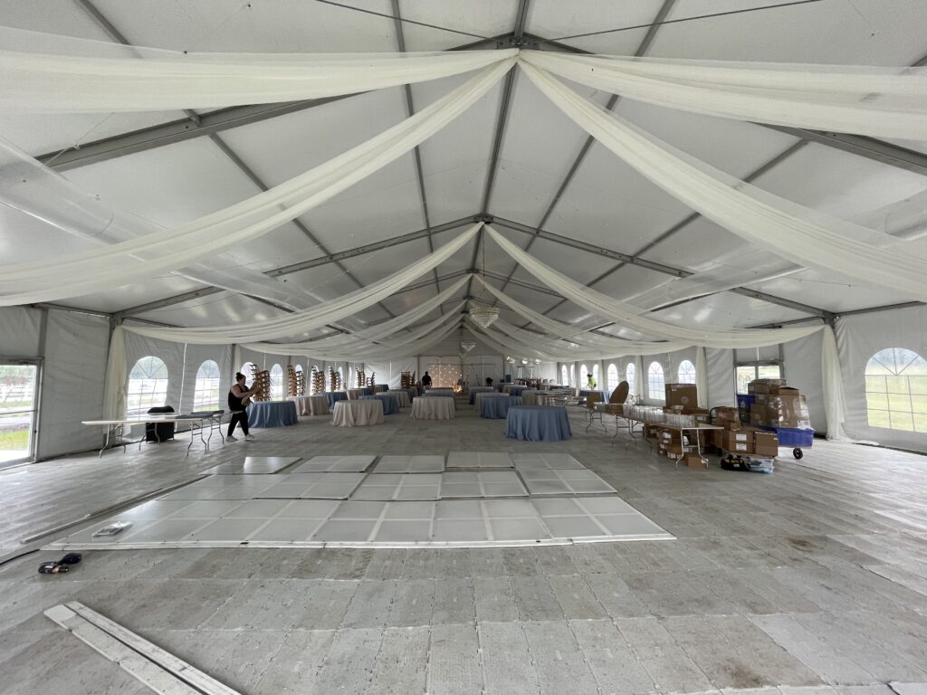 Under the 18m x 35m (60′ x 114′) Losberger clearspan temporary event structure with subflooring set up for a wedding reception