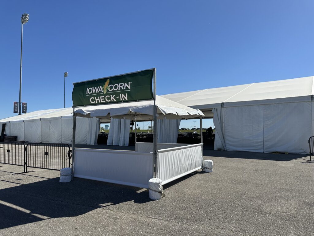 Iowa Corn checkin booth was an 10' x 10' frame tent with the pony walls with a 60' x 162' clearspan tent in the background - 2024 NASCAR Race Weekend at Iowa Speedway in Newton, Iowa