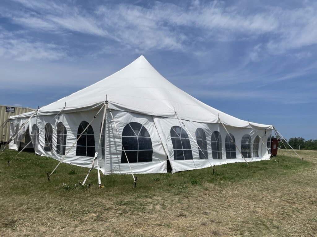 Tram schedule waiting tent with a 40' x 40' rope and pole tent (one of several) - 2024 NASCAR Race Weekend at Iowa Speedway in Newton, Iowa