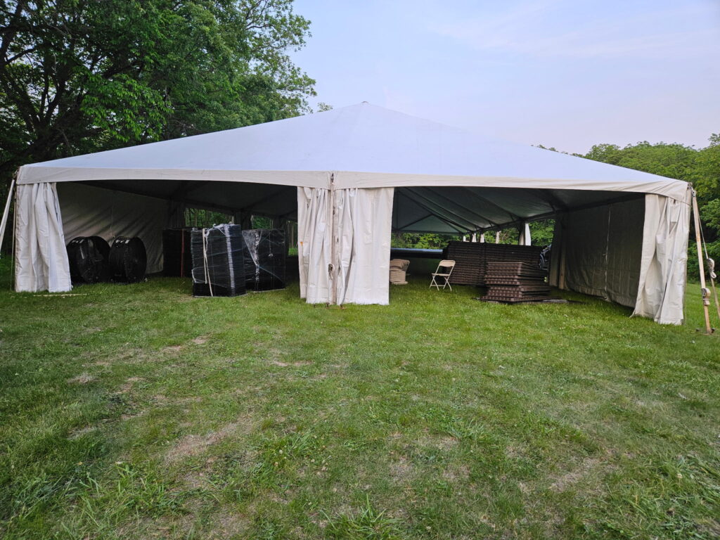 The end of 40' x 120' Hybrid Jumbo Track Tent with table, chairs and stage at Quad City Hindu Temple in Rock Island, Illinois