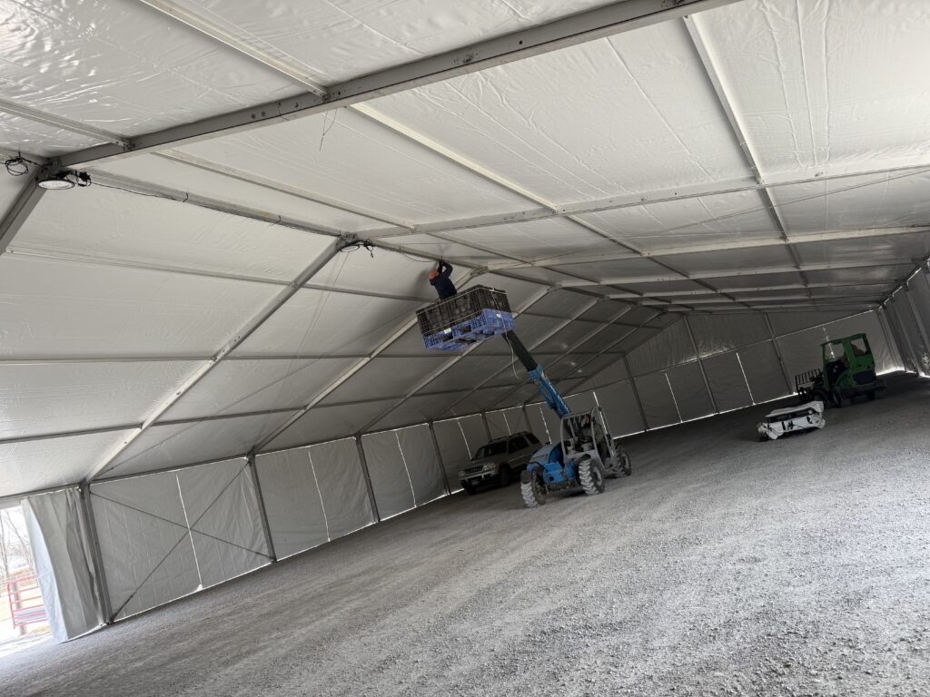 Crew working on UFO lights under the Under the 60' x 230' (18m x 70m) Losberger clearspan in Kalona, Iowa - Kalona Special Workhorse Sale
