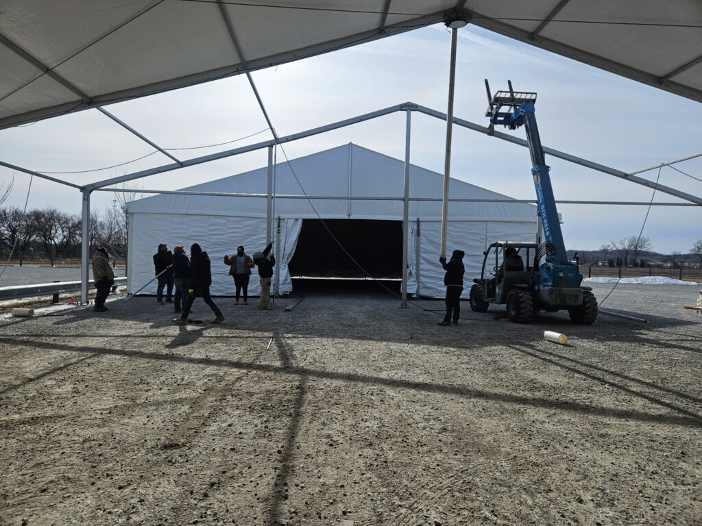 Crew working with a telehandler finsihing up the 60' x 230' (18m x 70m) Losberger clearspan structure.