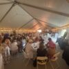Back corner with a crowd of people seated at round tables under a 40′ x 120′ Jumbo Track event tent in Iowa.