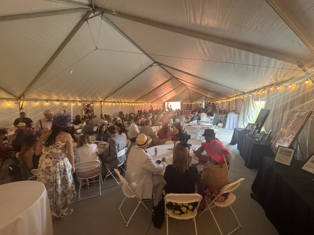 Back corner with a crowd of people seated at round tables under a 40′ x 120′ Jumbo Track event tent in Iowa.