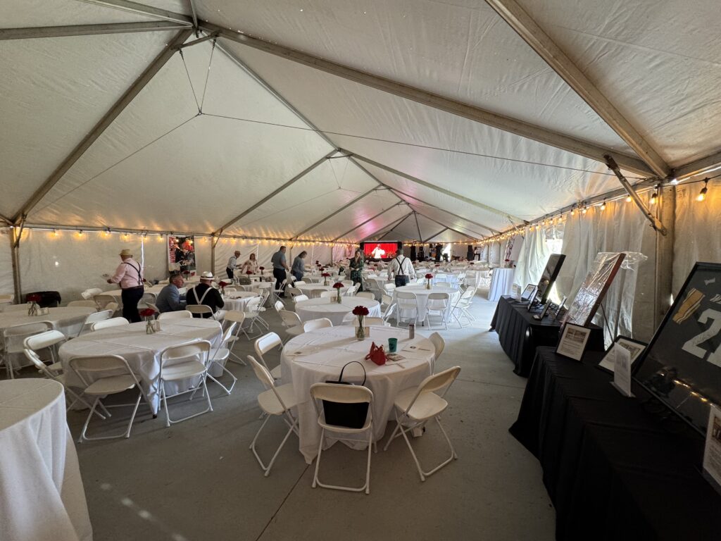 Round tables and folding white chairs under a 40′ x 120′ Jumbo Track event tent in Iowa.