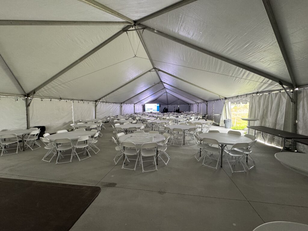 Under the 40′ x 120′ Hybrid Jumbotrac Event Tent with tables and chairs.