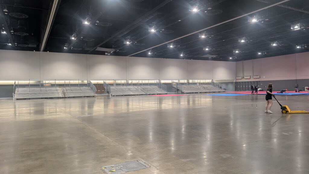 Bleachers in the background with event staff positioning blue and pink foam puzzle mats for safe sparring and forms at the WTSDA World Championships.