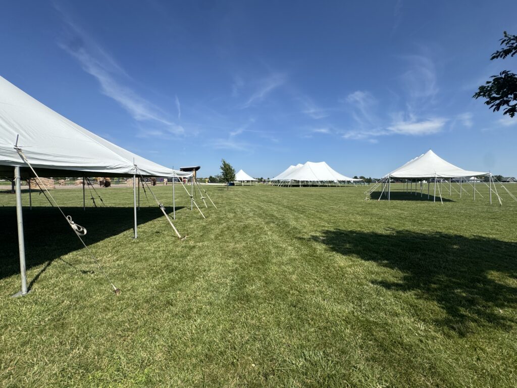 Multiple Rope and Pole Event Tents set up for North Liberty Blues & BBQ at Centennial Park with the Hy-Vee Center amphitheater in the background